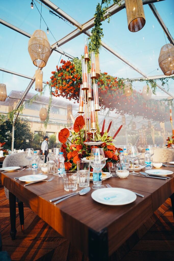 pexels photo 12946948 12946948 Luxurious table setting for a wedding under a transparent tent with floral arrangements and hanging lights.