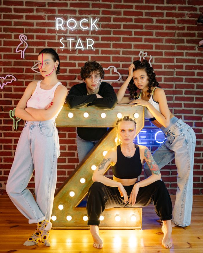 pexels photo 7312350 7312350 Fashionable group of Gen Z posing with neon lights and art makeup against a brick wall.