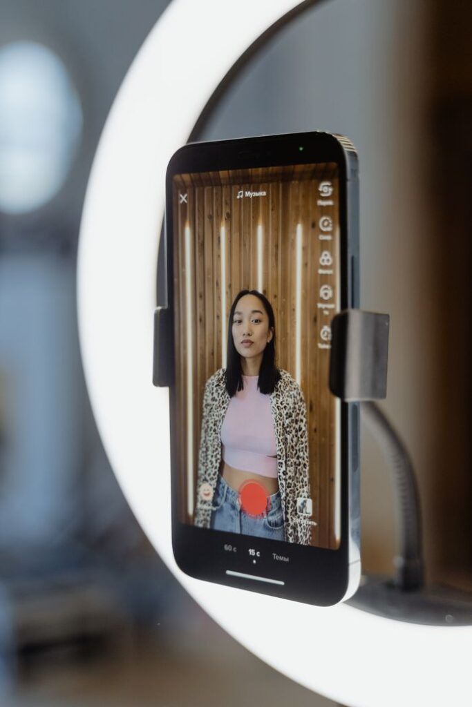 pexels photo 7481997 7481997 Teenage girl livestreaming content indoors using a smartphone and ring light.